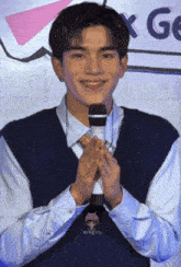 a young man holding a microphone in front of a sign that says ' x ge '
