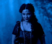 a woman in a black dress is standing in a dark room with a blue background