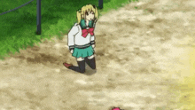 a girl in a school uniform is kneeling down on the ground in a field .