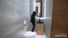 a woman stands in a bathroom next to a toilet and a sink made in animatica