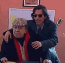 a man in a suit and sunglasses is hugging another man .