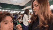 a woman is applying makeup to a man 's face in a dressing room .