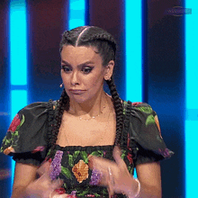 a woman in a floral dress is making a funny face on a television show .