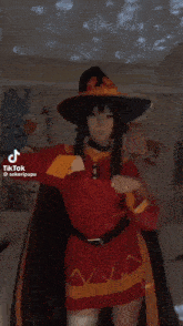 a woman in a red dress and a black hat is dancing in a room .