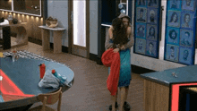 a man and a woman are hugging in a room with a lot of pictures on the wall .
