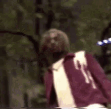 a man in a red jacket and white shirt is standing with his arms outstretched .