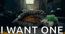 a clown is laying on the ground with the words `` i want one '' written on the bottom .