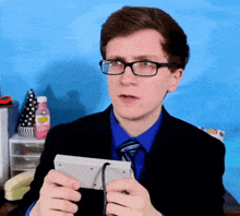 a man wearing glasses and a blue shirt is holding a white box