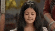 a little girl is making a funny face with her eyes closed while a woman holds her hair .