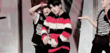 a man in a red and black striped sweater is standing next to another man in a black and white striped shirt .