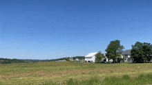 a white barn sits in the middle of a field