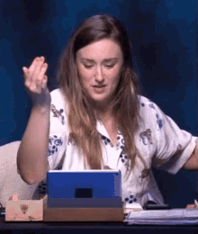 a woman is sitting at a desk with a tablet in front of her ..