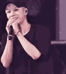 a young man is singing into a microphone while wearing a hat and headphones .