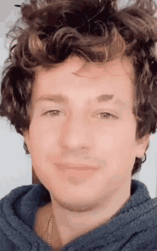 a man with curly hair and a necklace around his neck