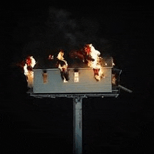 a group of people are sitting on top of a billboard that is on fire .