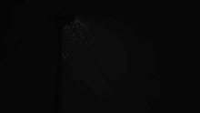 a person is standing in a dark room with a light shining through a window .