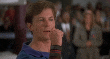 a man in a blue shirt is pointing at something in front of a crowd .