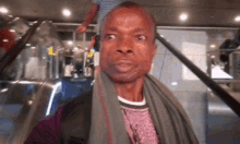 a man with a scarf around his neck is standing on an escalator looking at the camera