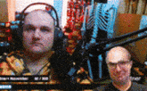 a man wearing headphones is talking into a microphone in front of a skeleton