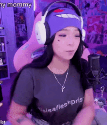 a woman wearing headphones and a purple hat is sitting in front of a microphone in a pink chair .