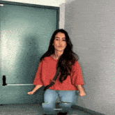 a woman in a red shirt is dancing in front of a door