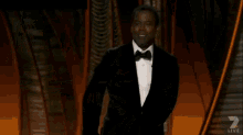 a man in a suit walks across a stage with the words live behind him
