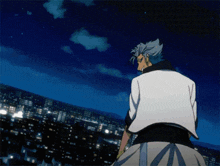 a man in a white jacket is standing in front of a city at night