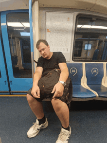 a man sleeping on a subway car with the letter m on it