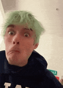 a boy with green hair is making a funny face .