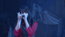 a woman in a red jacket is singing into a microphone on stage .