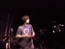 a man in a purple shirt is dancing on a stage in a dark room .