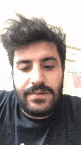 a man with a beard is wearing a black shirt that says ' a ' on it