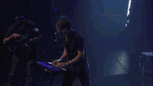a man in a black shirt is playing a keyboard in a dark room