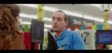a man in a blue shirt is holding a piece of paper in a store .