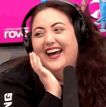 a woman wearing headphones is laughing in front of a microphone