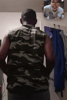 a man in a camo shirt is looking at another man