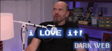 a man sitting in front of a microphone with the words i love it dark web on the bottom