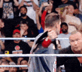 a man is holding a microphone in a wrestling ring with a crowd watching .