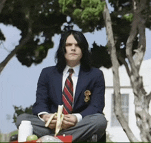 a man in a suit and tie is sitting in a lotus position holding a banana