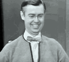 a black and white photo of a man wearing a bow tie and glasses .