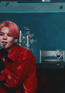 a man with pink hair is wearing a red jacket and a microphone in his mouth ..