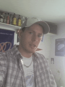a man wearing a plaid shirt and a baseball cap is taking a selfie