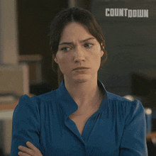 a woman in a blue shirt with her arms crossed has the word countdown on the bottom right