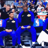 a man wearing a lakers jersey sits in a chair