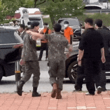 a group of men in military uniforms are walking down a brick sidewalk
