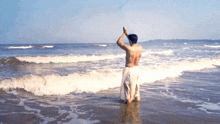 a man in a white towel is kneeling in the water on the beach