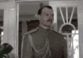 a man in a military uniform stands in front of a window