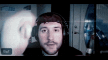 a man wearing headphones is looking at another man in front of a big t sign