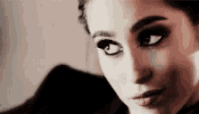 a close up of a woman 's face with smokey eyes and a nose ring .