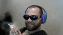 a man wearing sunglasses and headphones holds a cigarette in his hand